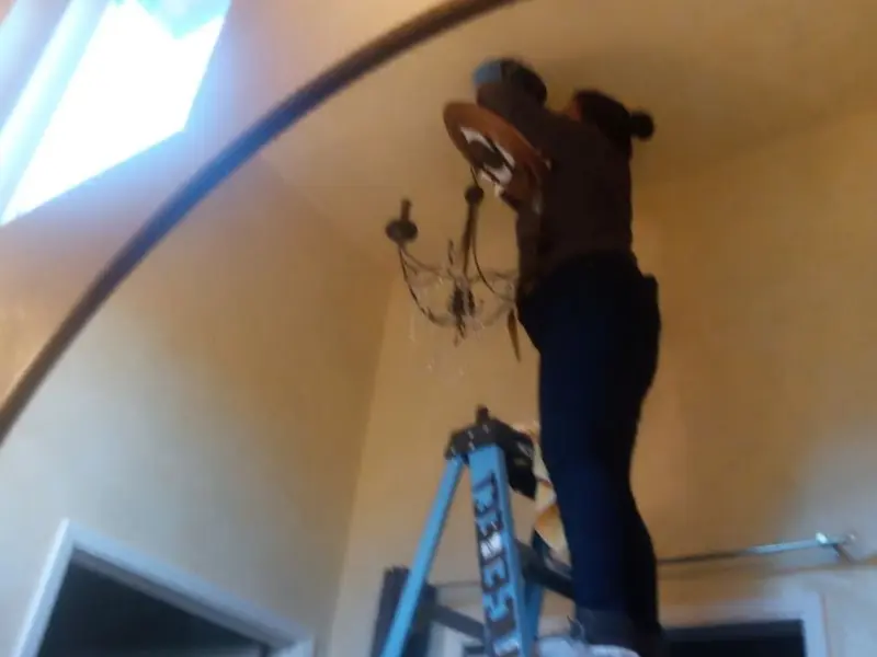 Electrician installing a chandelier in a Briar residence